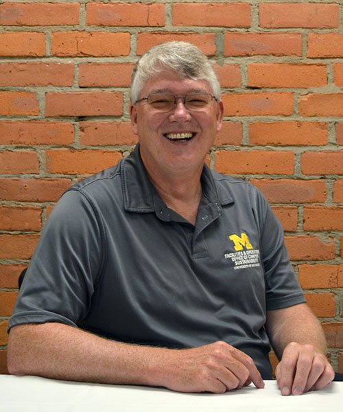 Staff headshot Ken Keeler, in front of a brick background.