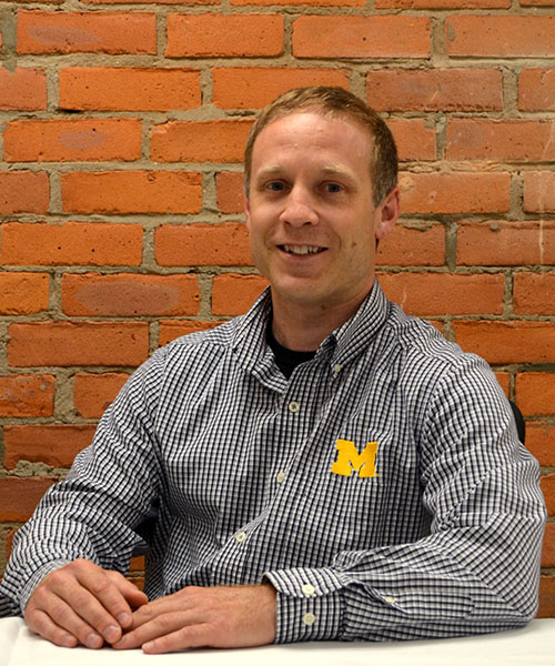 Staff headshot Matt Peterson, in front of a brick background.