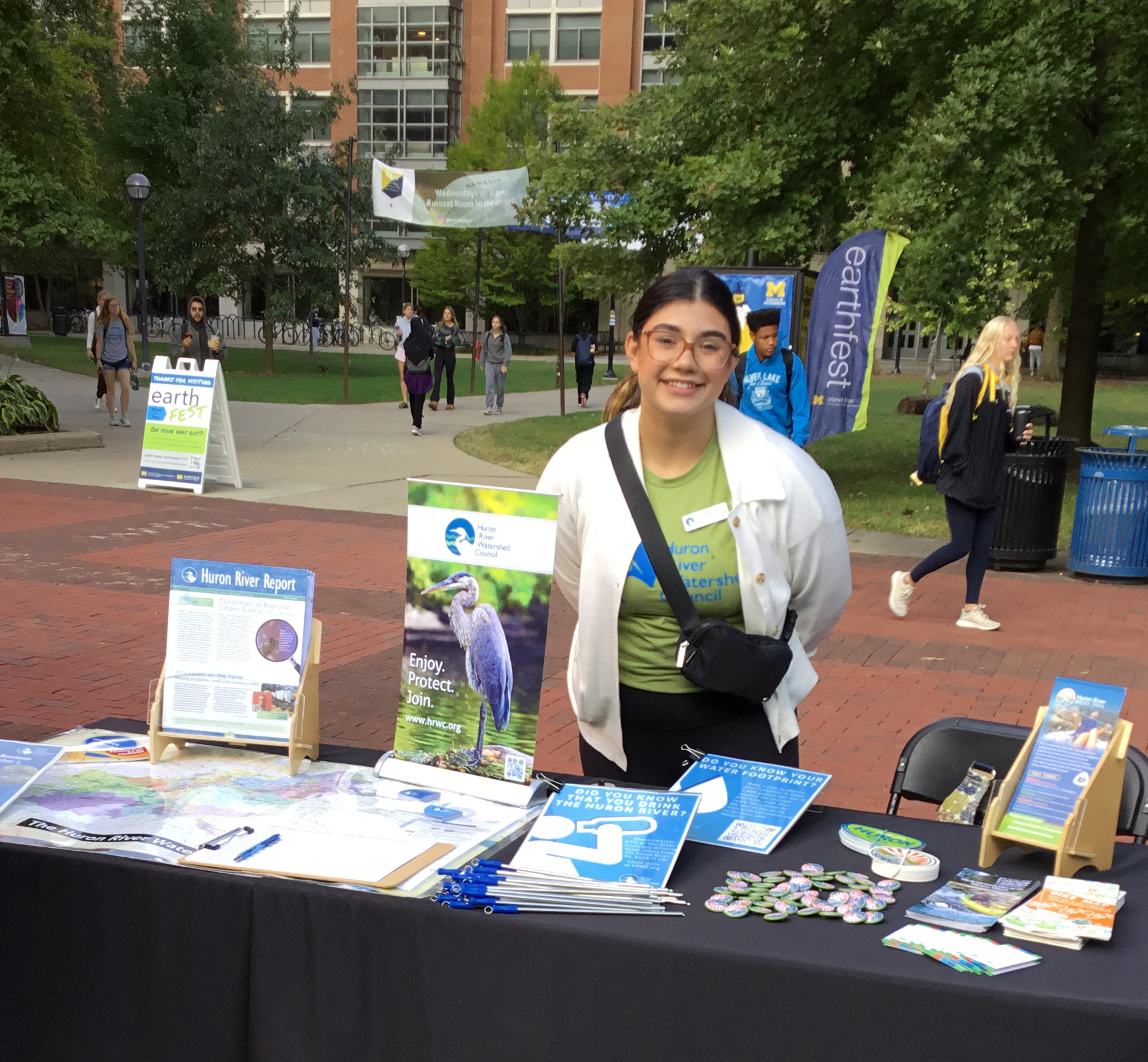 Volunteer at Earthfest table handing out literature on the diag.